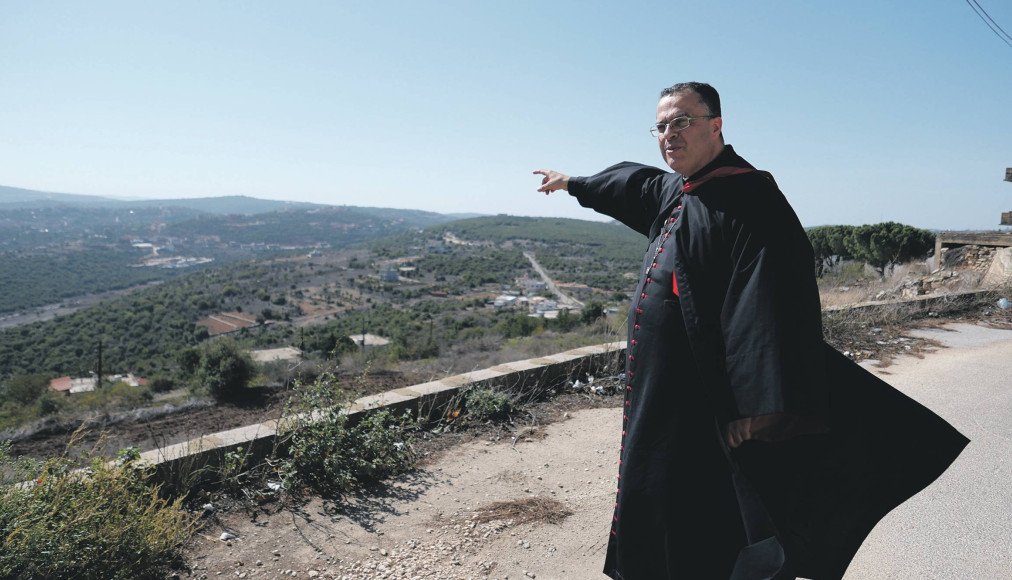 L’archevêque maronite de Tyr, Monseigneur Abdallah, montre la frontière avec Israël, située au sommet de la colline visible au loin. L’archevêque maronite de Tyr, Monseigneur Abdallah, montre la frontière avec Israël, située au sommet de la colline visible au loin. / ©Gaby Leygues