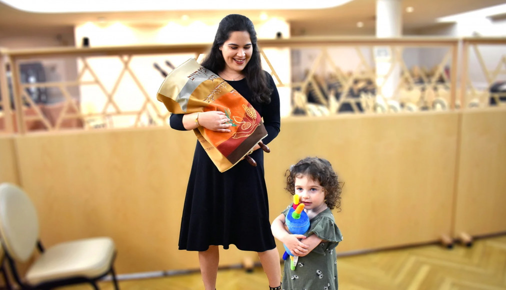 Une femme juive orthodoxe tient un rouleau de la Torah tandis que sa fille embrasse un jouet de la Torah. Une femme juive orthodoxe tient un rouleau de la Torah tandis que sa fille embrasse un jouet de la Torah. / RNS